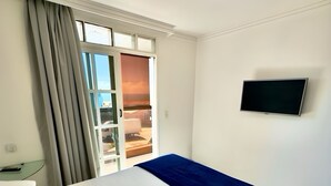 A hotel room with a bed, a TV mounted on the wall, and a window with curtains. - Las Brisas Beach Hotel (Natal)