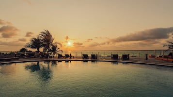 Relax by the pool, surrounded by lounge chairs and umbrellas, with the ocean just steps away.