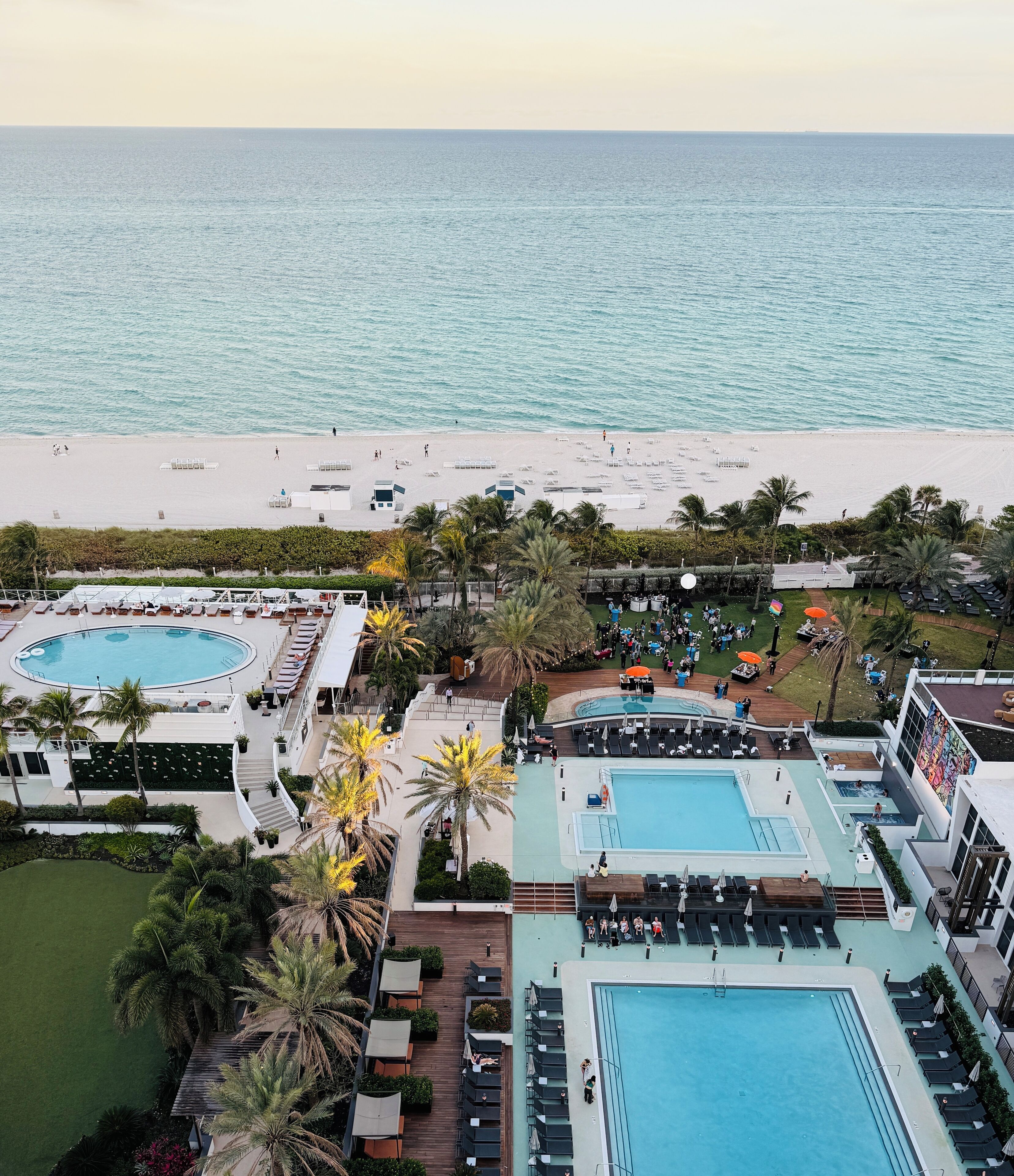 A resort with multiple swimming pools, a beach, and palm trees.