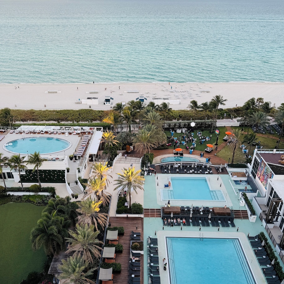 A resort with multiple swimming pools, a beach, and palm trees.