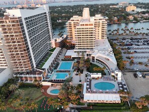 A high-rise hotel with multiple swimming pools, a beach area, and a marina.