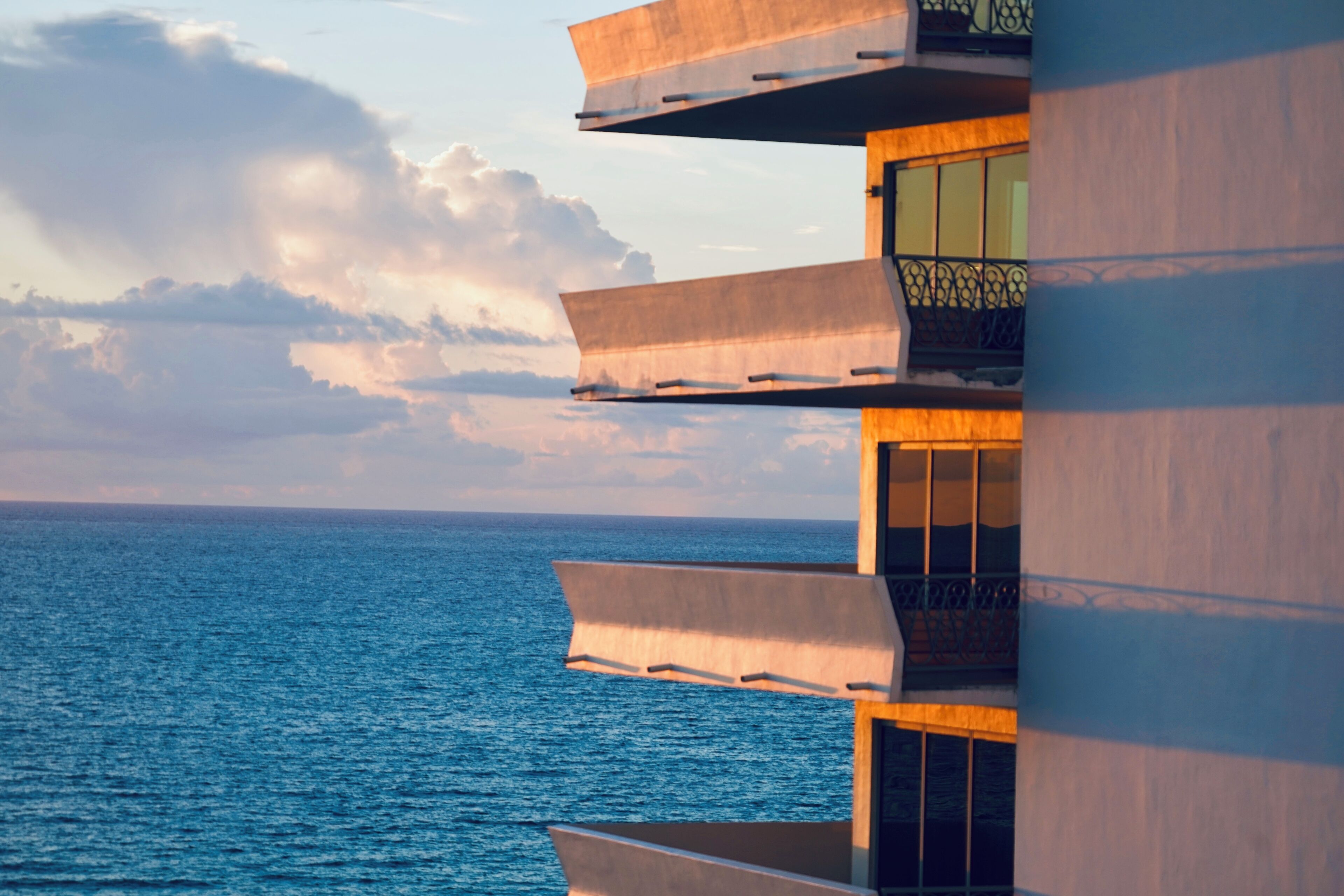 A modern building with balconies overlooking a body of water.