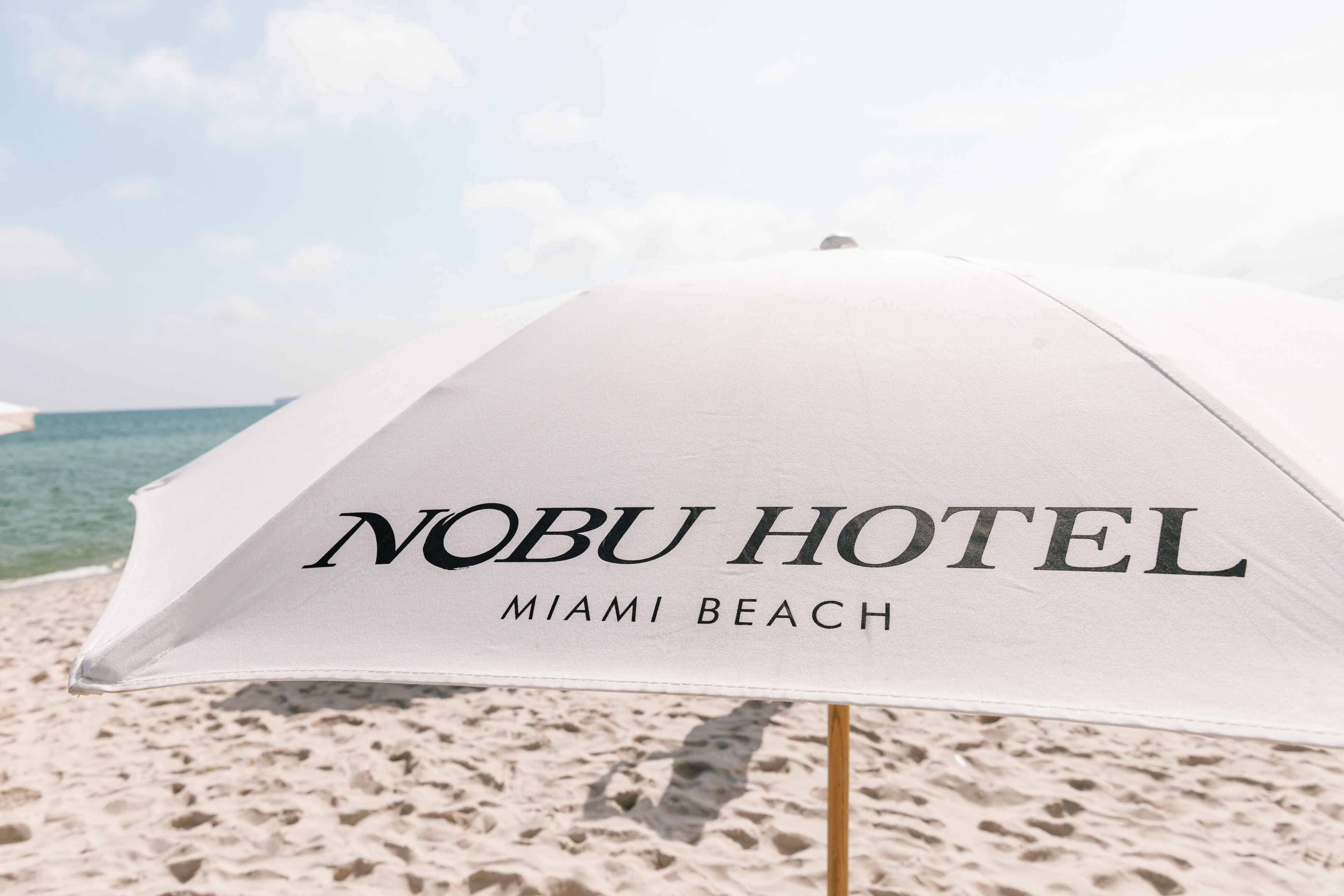 A beach umbrella with "Nobu Hotel Miami Beach" written on it.