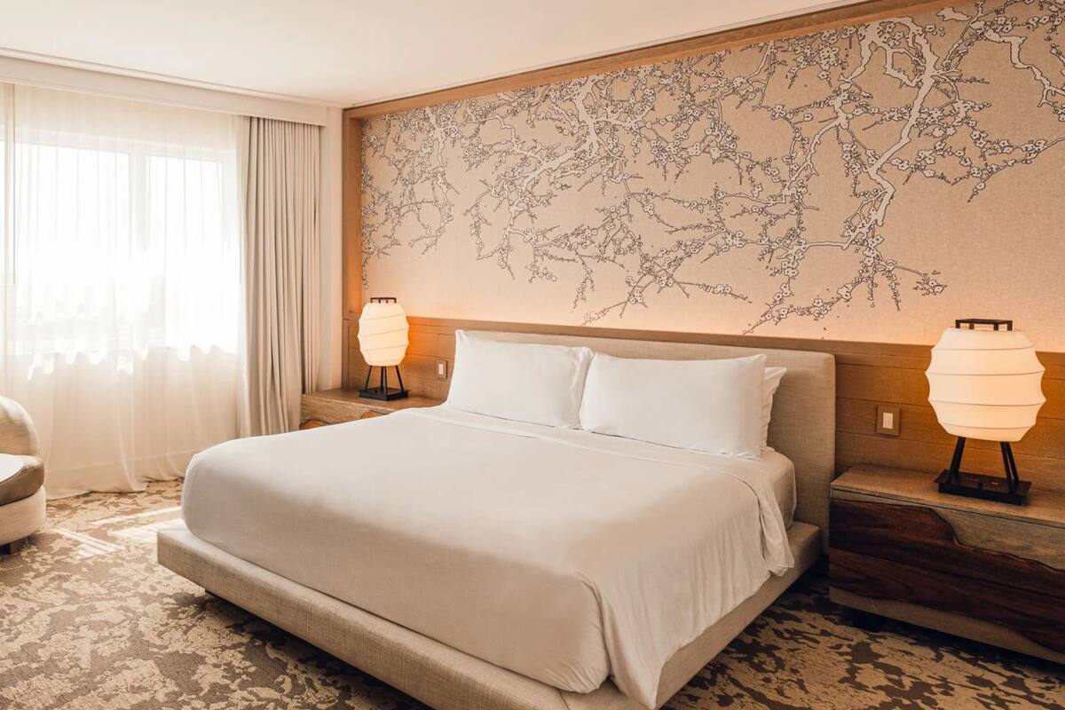 Una habitación de hotel con cama, sofá, una mesita y una mesita de noche con lámparas.