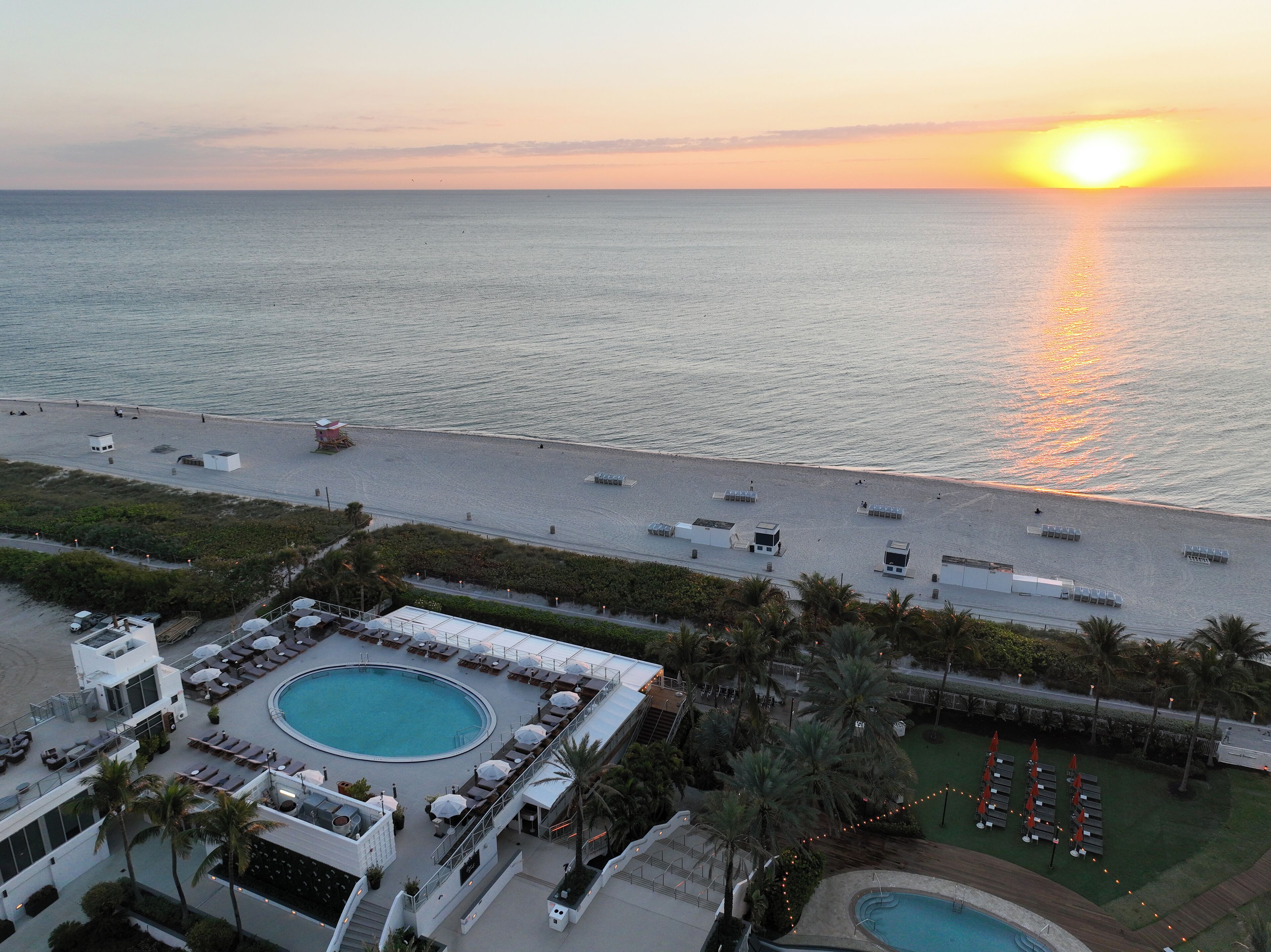 A resort with a pool, beach, and sunset view.