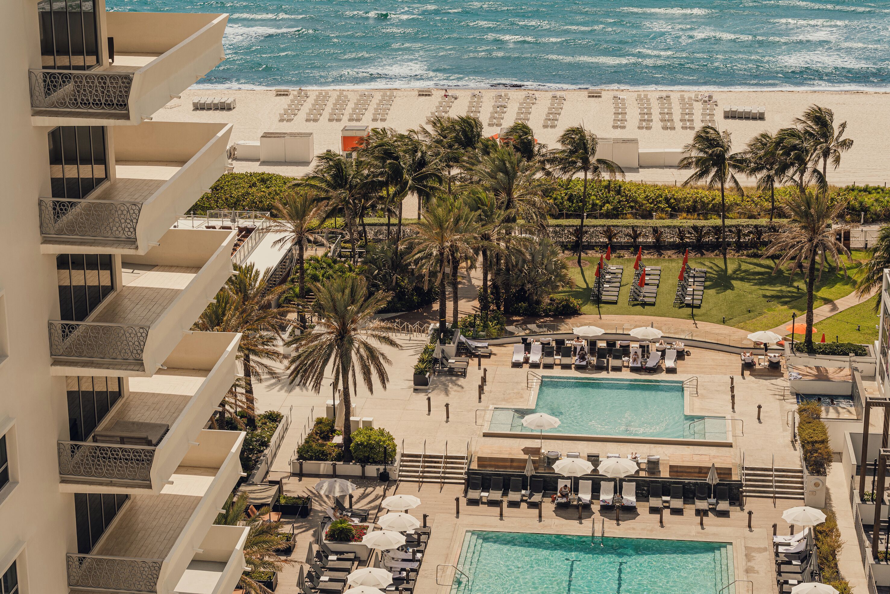 A resort with a pool area, beach access, and a view of the ocean.