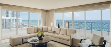 Un salón amplio con un ventanal que ofrece vistas al mar y un edificio de gran altura.
