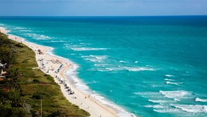 A beach with a long stretch of sand, a few umbrellas, and people. - Nobu Hotel Miami Beach (Miami Beach)