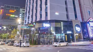 Ein modernes Hotel mit einem großen 'Dubai'-Schild, mehreren Etagen und einer Glasfassade.