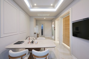Un área de comedor moderna con una mesa, sillas y un televisor en la pared.
