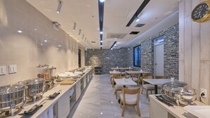 Ein moderner Essbereich mit Backsteinwand, mehreren Tischen und Speiseausgaben in Buffetform.