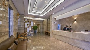 Eine moderne Hotellobby mit Empfangstresen, Ledersitzgelegenheiten und freundlicher Beleuchtung.