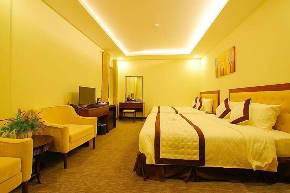 A hotel room with a large bed, a desk, a chair, and a television.