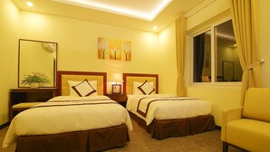 Habitación de hotel con dos camas, una mesita de noche con lámpara, un espejo grande y una ventana con cortinas.