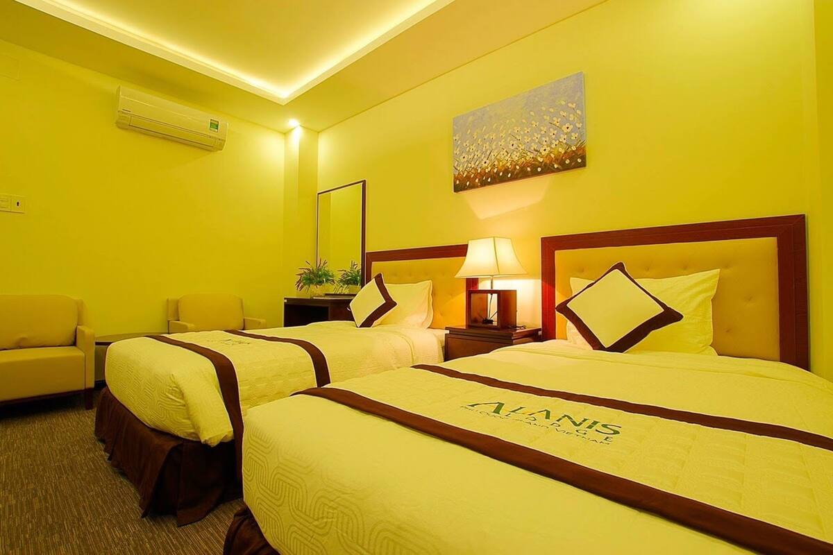 A hotel room with two beds, a sofa, a lamp, and a painting on the wall.
