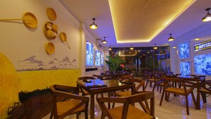 Un restaurante con mesas y sillas de madera, una planta grande y un techo con textura.