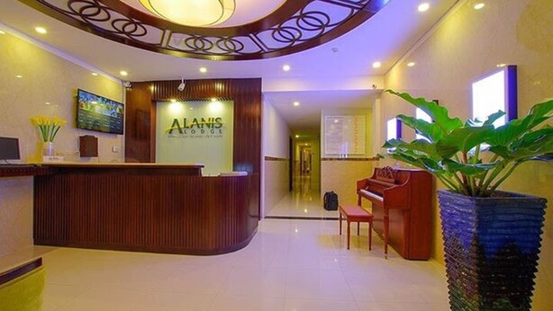 Un vestíbulo de hotel con mostrador de recepción, un piano y una gran planta en maceta.