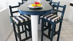 A dining table with chairs, a pitcher, and a plate of fruit.