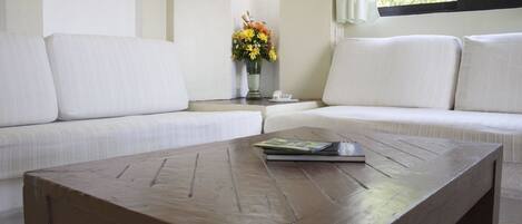 A living room with a sofa, a coffee table, and a vase with flowers.