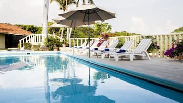 Alberca al aire libre, sombrillas en la alberca y camastros