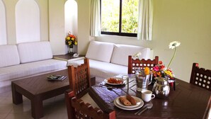 A dining area with a wooden table, chairs, a sofa, and a window with curtains.