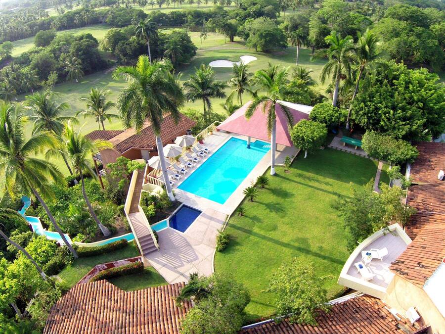 Un resort con piscina, sillas de descanso y palmeras.