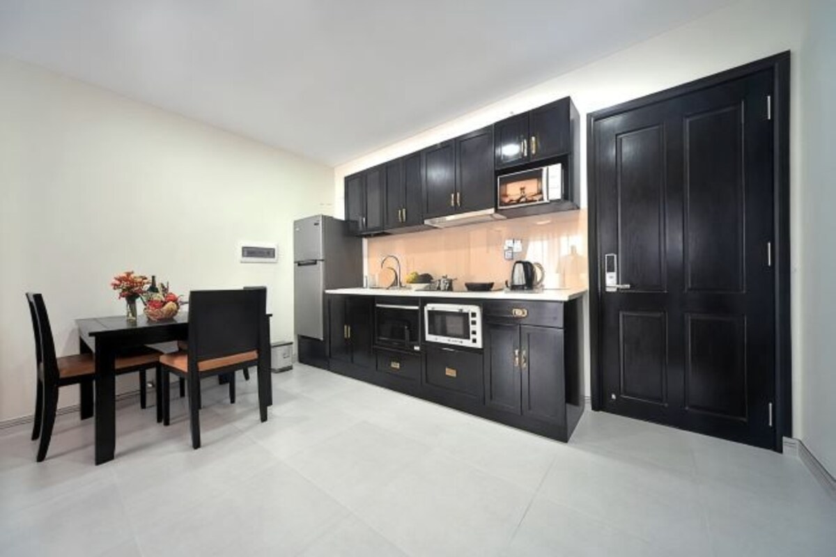A compact kitchen with dark cabinetry, a microwave, and a dining area with a table and chairs.