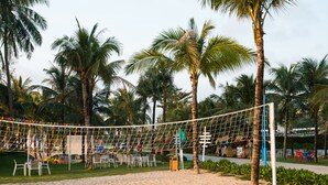 A beach volleyball court with a net, palm trees, and outdoor seating. - Kosmos Apart Hotel (Phu Quoc)