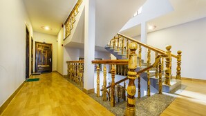 A spacious hallway with a wooden floor leading to a staircase with a wooden handrail and a stone balustrade. - Thanh Trung Hotel (Phu Quoc)