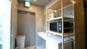 Un baño pequeño con inodoro, lavamanos y un microondas en un estante.