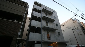 Un edificio de varios pisos con acceso a nivel de calle, balcones y señalización visible.