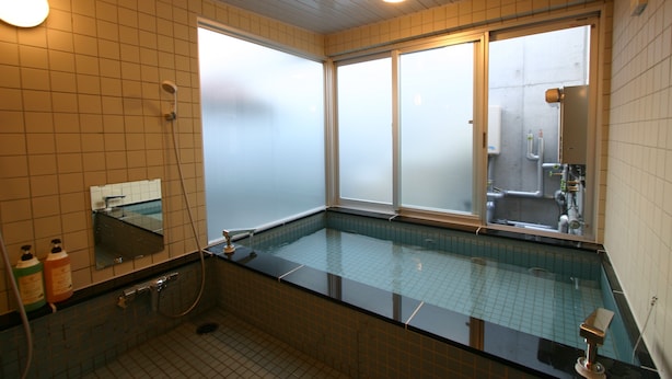 Un baño moderno con ducha envuelta en vidrio, un espejo grande y vistas a través de ventanas con vidrio esmerilado.