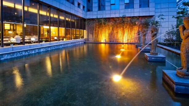 A modern hotel lobby with a reflective pool, stone statues, and a warm-lit wall. - Narada Boutique hotel Nanchang Red Bull (Nanchang)