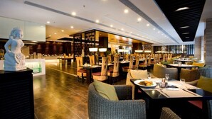 A modern restaurant with a central bar area, multiple dining tables, and a statue on the left. - Narada Boutique hotel Nanchang Red Bull (Nanchang)