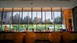 A bar area with wicker chairs, large windows, and a view of greenery outside. - Narada Boutique hotel Nanchang Red Bull (Nanchang)
