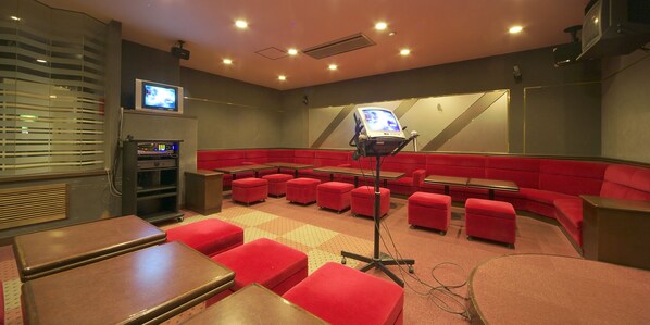 A theater with red seating, a control panel, and a projection screen.