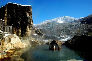 Una fuente termal natural rodeada de rocas y montañas nevadas.