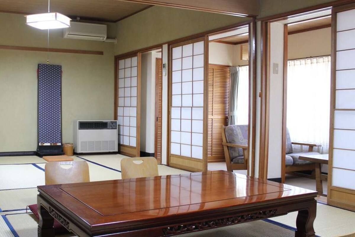 Een traditionele Japanse kamer met tatami vloerbedekking, een houten tafel, schuifdeuren en een futon.