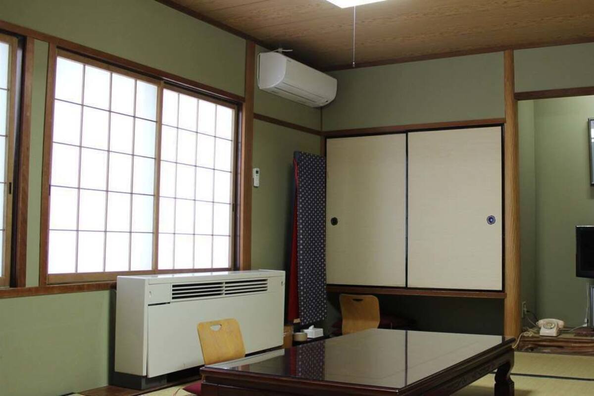 Een traditionele Japanse kamer met tatami vloeren, een schuifdeur, een televisie en een verwarming.
