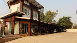 A two-story building with a covered porch and a carport. - Pornkasem House (Chiang Rai)