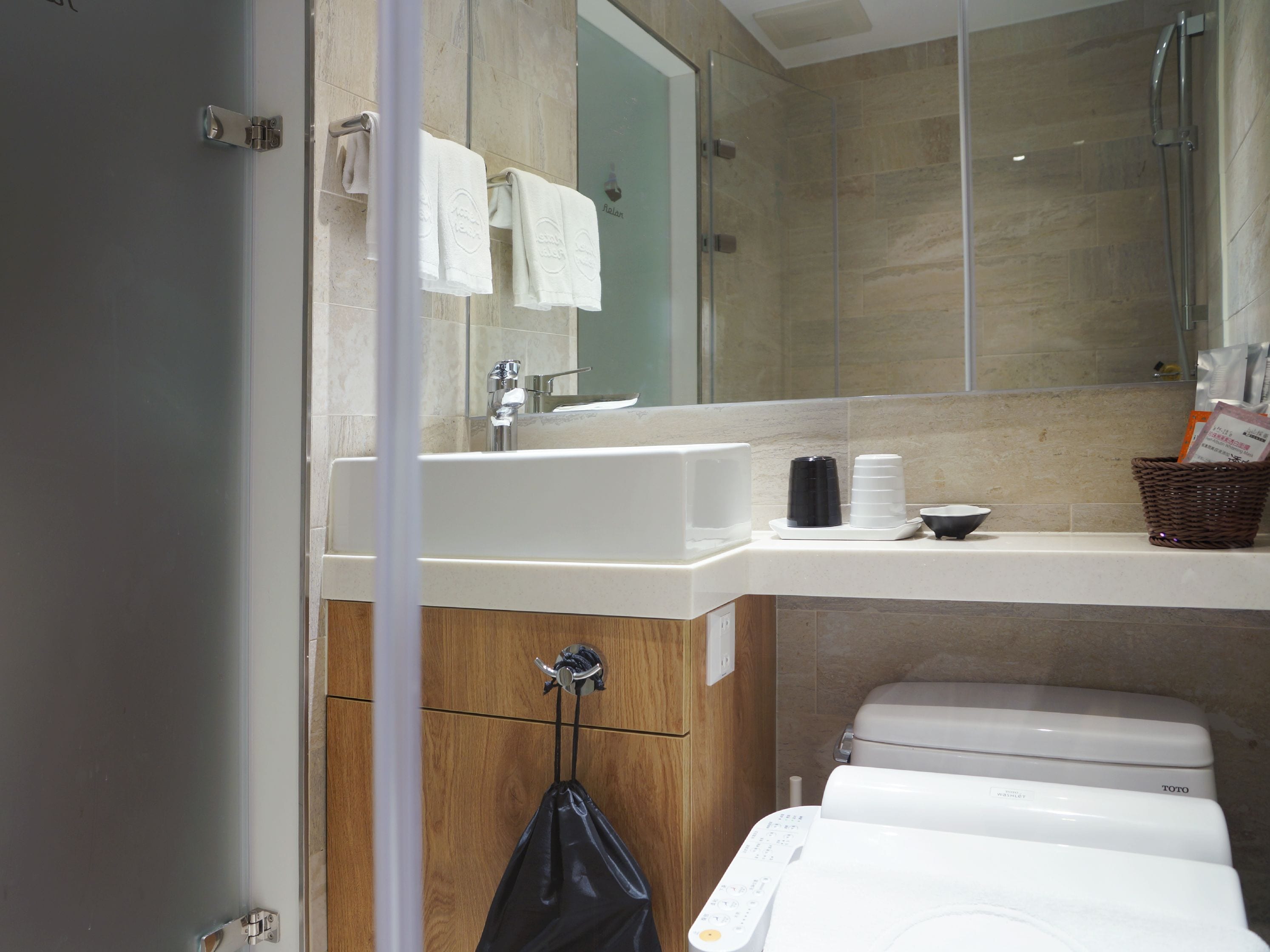 Ein modernes Badezimmer mit einem großen Spiegel, einem weißen Waschbecken und einer Toilette.