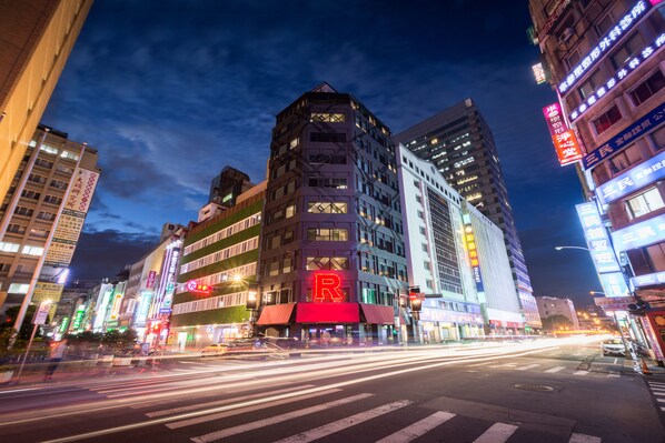 A multi-story building with illuminated signage, including a prominent 'R' sign on the facade.