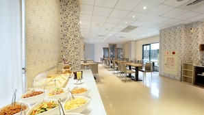 A buffet setup with various food items in bowls, arranged on a long table in a well-lit room with a tiled floor and patterned walls. - OHYA Chain Boutique Motel-Yongkang (Tainan)
