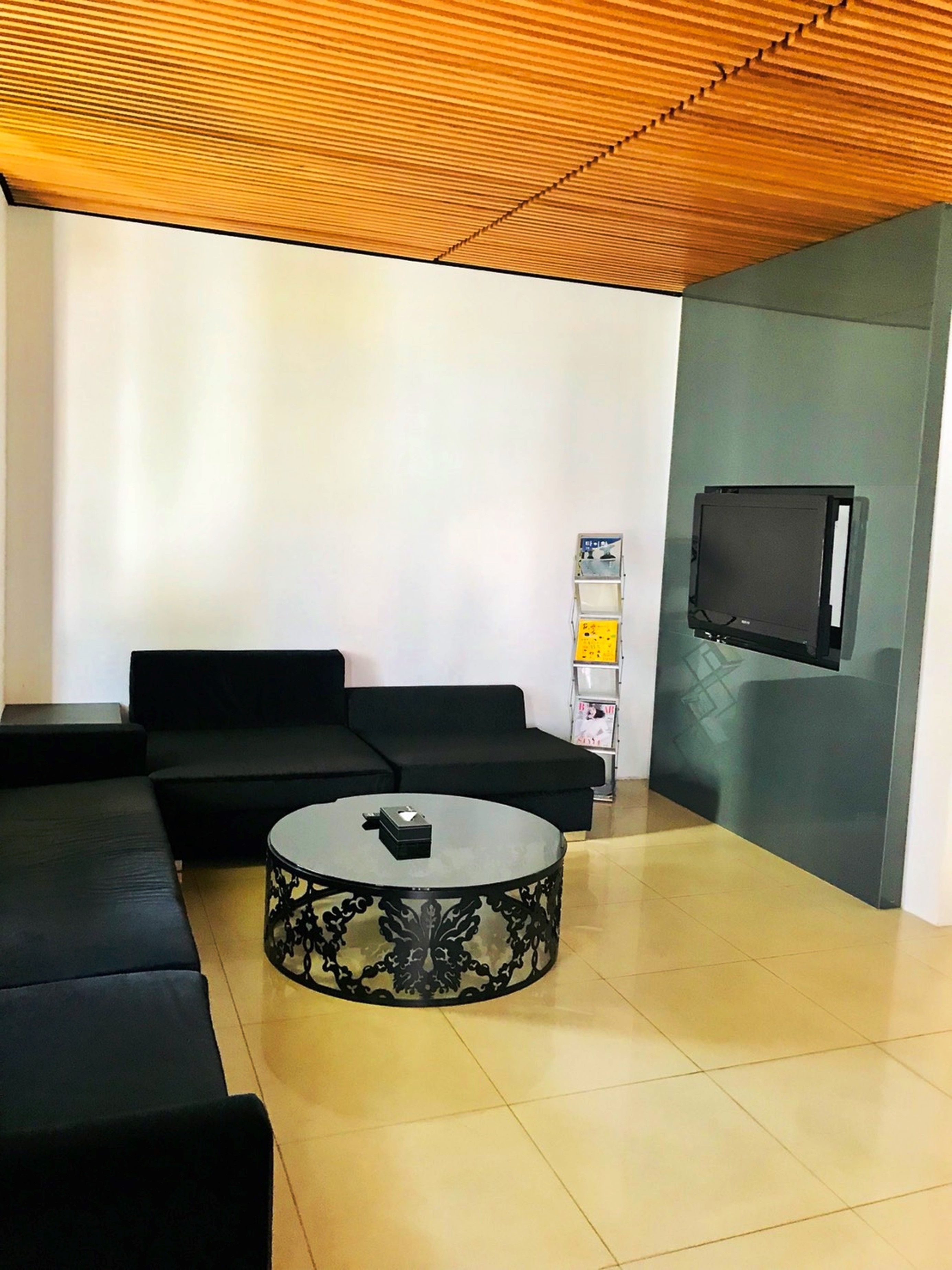Una sala de estar moderna con un sofá modular, una mesa de centro redonda y un televisor de pantalla plana montado en la pared.