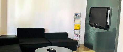 Una sala de estar moderna con un sofá modular, una mesa de centro redonda y un televisor de pantalla plana montado en la pared.