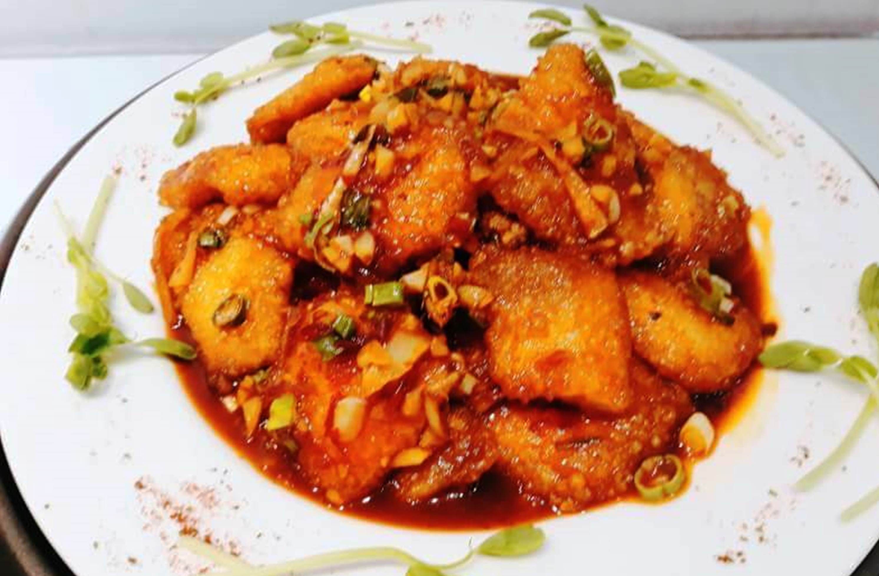 Un plato de comida con salsa roja, decorado con hierbas verdes y nueces.