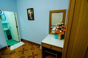 Un baño con suelo de madera, un lavamanos blanco, un espejo y un jarrón con flores.