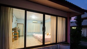 Een slaapkamer met een grote schuifpui, een bed en een klein tafeltje.