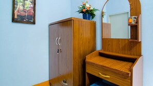 Een houten kast met een spiegel, een klein houten tafeltje en een lijst met een afbeelding aan de muur.