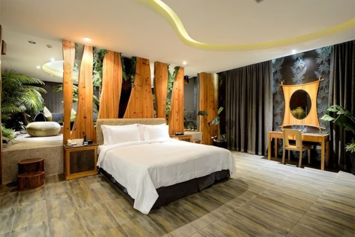 Une chambre à coucher comprenant un lit, des tables de chevet, un bureau avec une chaise et un grand miroir.